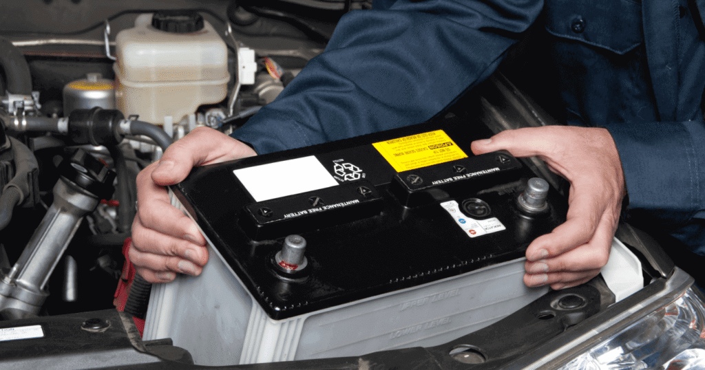 Mechanic installing a 12V car battery under the hood
